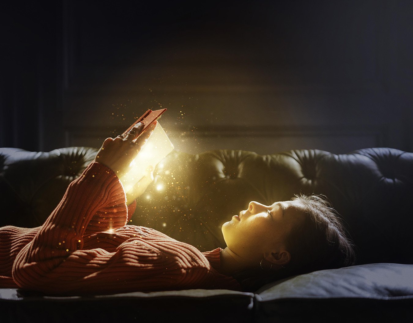Petite fille qui lit un livre allongé sur son canapé qui s'illumine